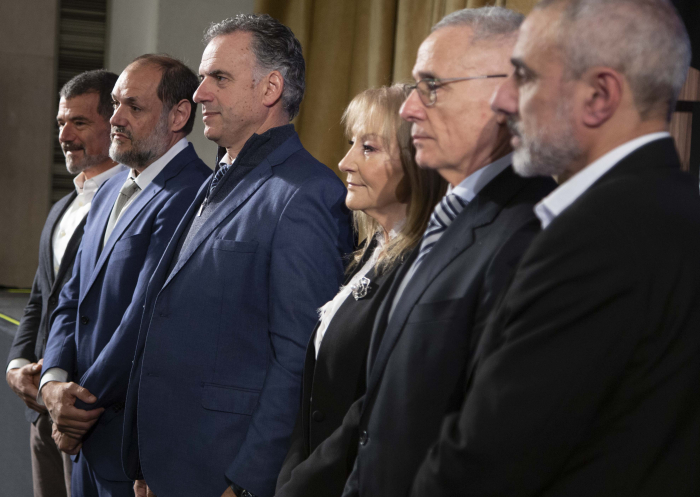 Presidente Orsi y vicepresidenta, de pie junto a otros participantes en una platea.