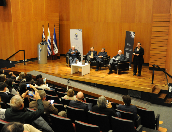 Cuatro personas sentadas en el escenario del salón de actos del anexo a Torre Ejecutiva, 