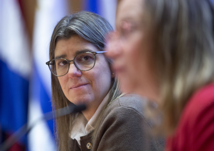 Ministra de Vivienda sentada en mesa con micrófono 