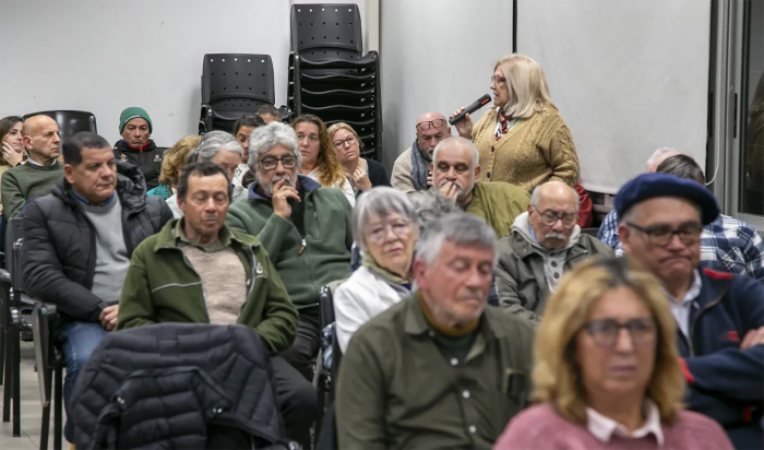 Personas sentadas en sillas miran hacia el frente. 