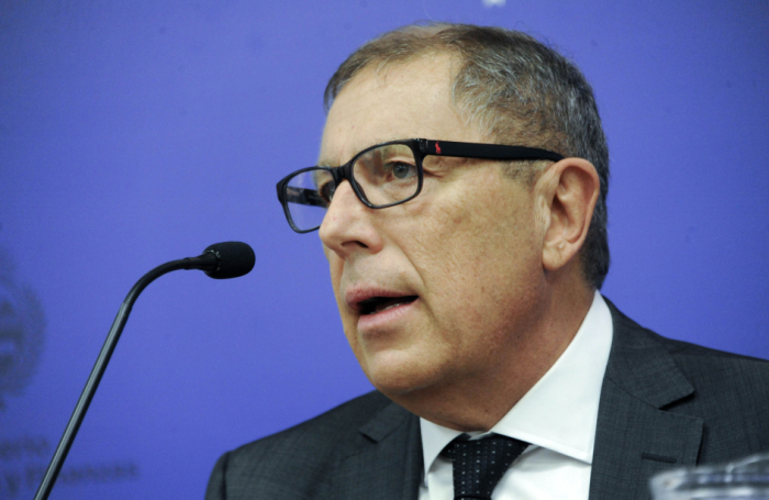 Ministro de Economía diserta sentado frente a un micrófono. 