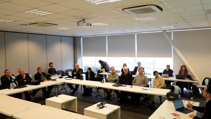Grupo de personas sentadas alrededor de una mesa blanca en forma de U