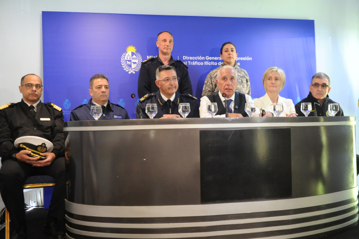 Ministro del Interior sentado en mesa con micrófono diserta en conferencia de prensa