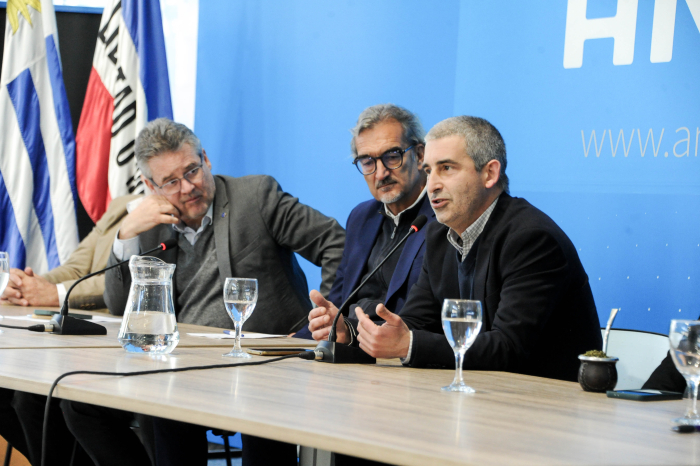 Presidente de la ANEP diserta sentado con micrófono en sala de conferencias 