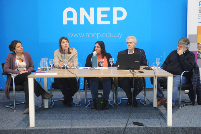 Autoridades y expertos en Educación sentados en mesa con micrófonos. Atrás cartel con logo