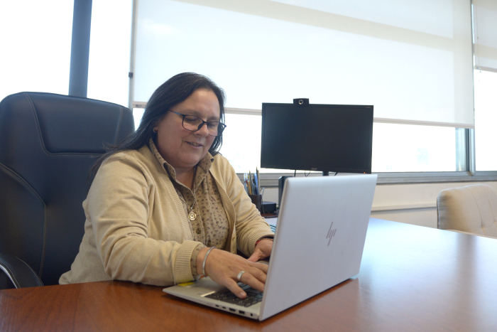 Subsecretaria sentada en su escritorio escribe en una computadora portátil.