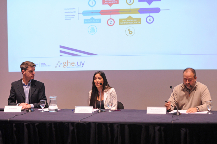 Tres técnicos de la Oficina Nacional de Servicio Civil sentados en mesa con micrófono.