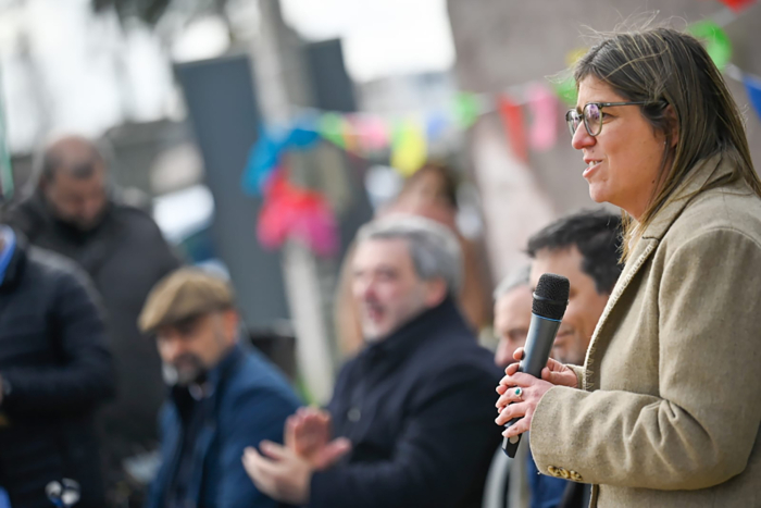 Ministra de Vivienda, de perfil, diserta parada con micrófono en mano. 