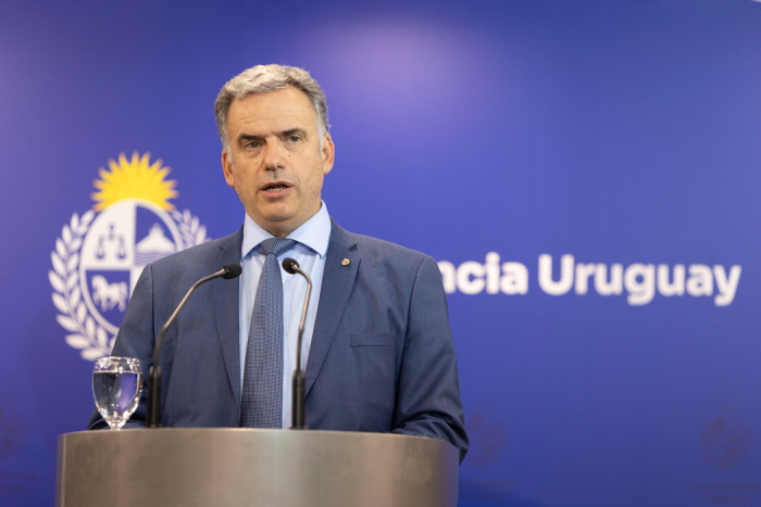 Orsi diserta parado en atril con micrófono en sala de conferencias de Presidencia. 