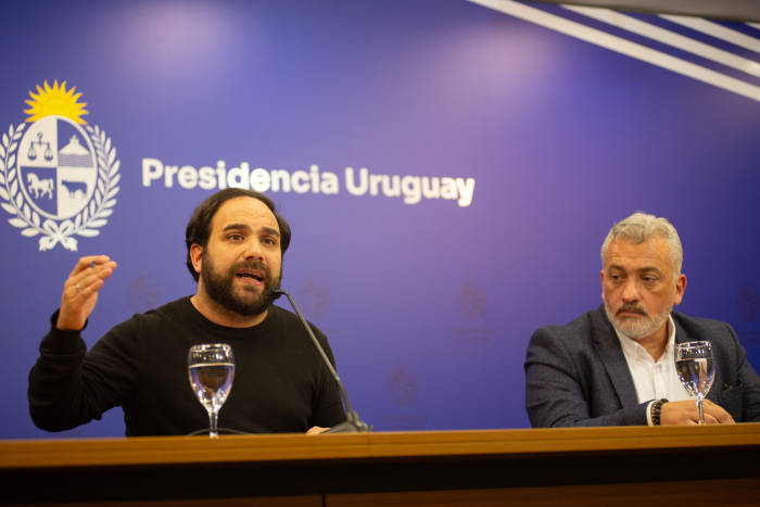Ministro de Desarrollo Social diserta sentado en mesa con micrófono