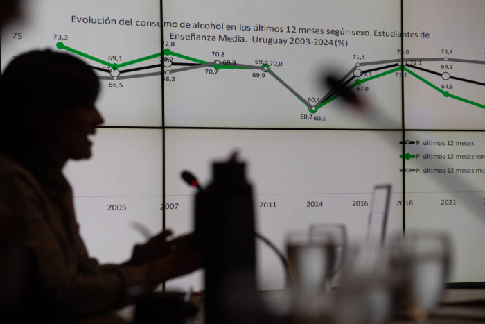 Experta diserta, sentada en mesa con micrófono, en la sala de conferencias de la ANEP. 