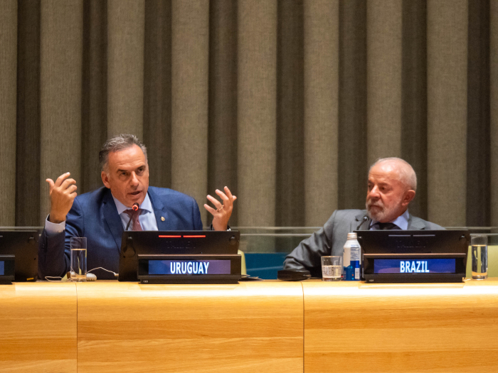 Orsi diserta en mesa con micrófonos y computadoras portátiles junto al presidente de Brasil.