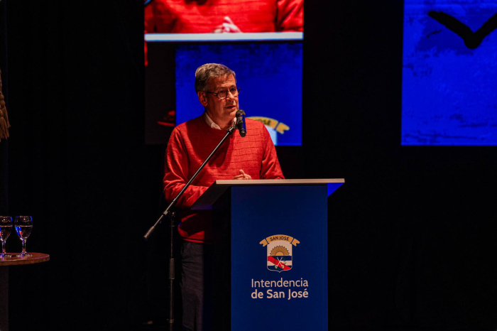 Prosecretario de Presidencia diserta parado en atril con logo de la Intendencia de San José 
