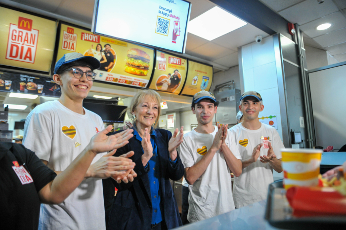 Cosse, junto a tres empleados de Mac Donalds, aplaude y mira hacia adelante en el mostrador. 
