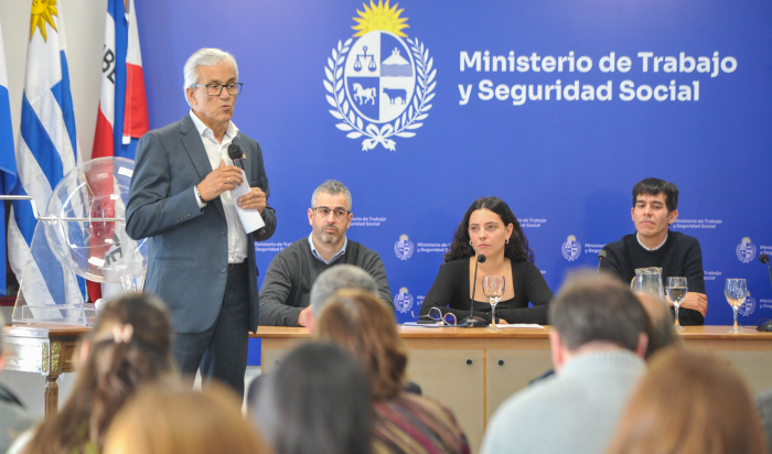 Ministro de Trabajo diserte de pie con micrófono en mano.