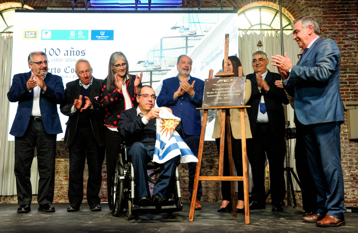 El Ministro de Turismo despliega la bandera de Uruguay en el puerto de Colonia y otras autoridades.