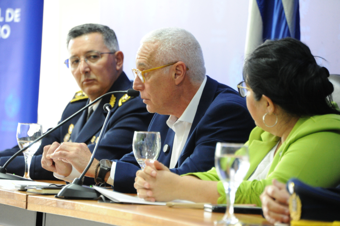 Ministro del Interior diserta sentado en mesa con micrófono.