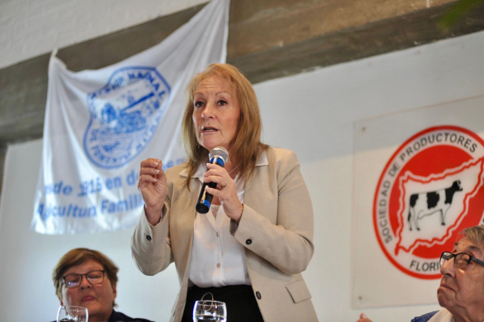 Cosse diserta de pie con micrófono en mano, junto a dos participantes. 