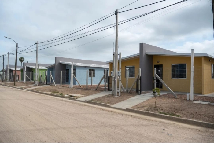 Hilera de casas recién construidas, de variados colores y diseño simple, a lo largo de una calle