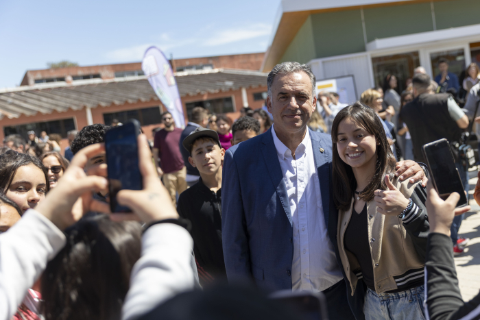 Orsi posa sonriente frente a cámara junto a una adolescente. Alrededor, varios adolescentes.