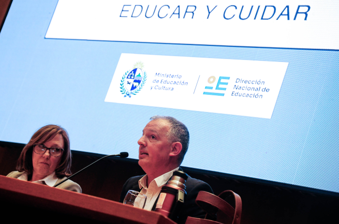 Director nacional de Educación diserta sentado en mesa con micrófono.