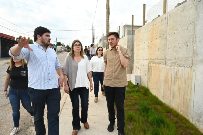 Ministra de Vivienda camina por una calle junto a otras personas mientras conversan. 