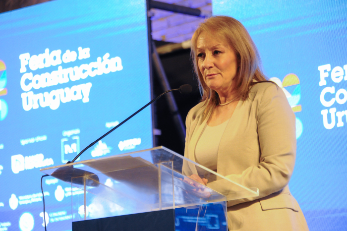 Cosse diserta de pie en la Rural del Prado, con un atril y un cartel azul.