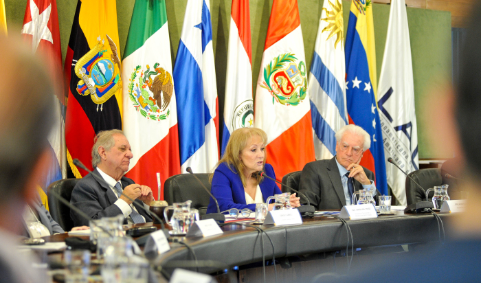 Cosse diserta sentada en mesa con micrófono junto a las autoridades de Aladi.