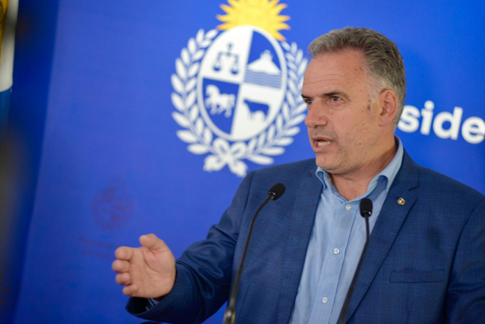 Presidente Orsi, sentado, diserta frente a dos micrófonos. Atrás se observa cartel azul con logo 