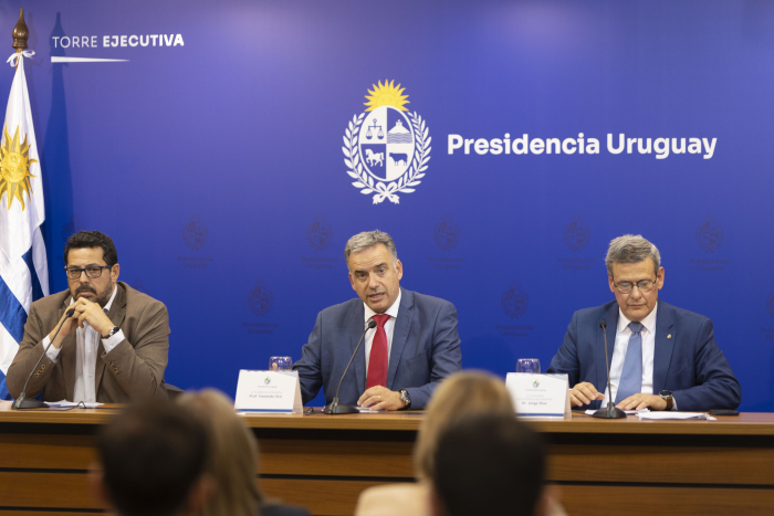 Orsi diserta sentado en mesa con micrófono en sala de prensa de Torre Ejecutiva. 