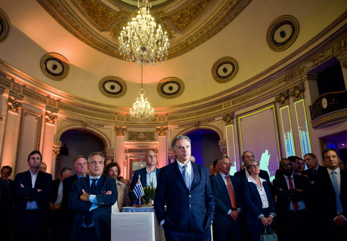 Orsi de pie, junto a autoridades de gobierno y público en general, mirando hacia adelante.