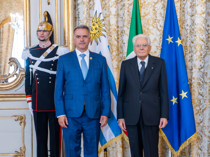 Los presidentes de Uruguay e Italia se estrechan la mano y sonríen a la cámara.
