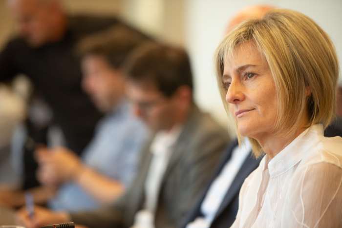 La Ministra de Vivienda diserta sentada en una mesa, junto al Ministro del Interior y autoridades.