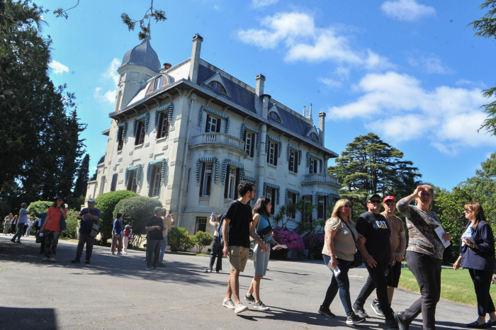 Pérgola de metal en forma de túnel, con mucha vegetación y bancos, en el jardín de la residencia