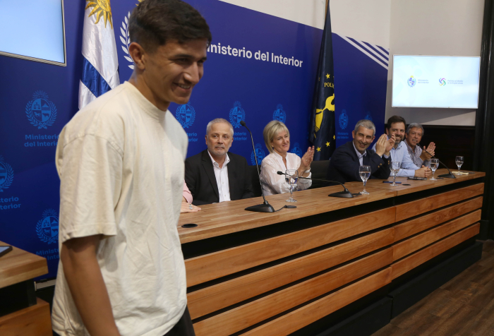 Joven participante de Pelota al Medio, de pie, sonríe al público.