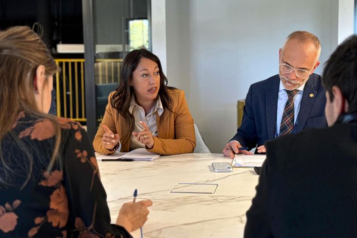 Ministra de Industria diserta sentada junto a otras personas