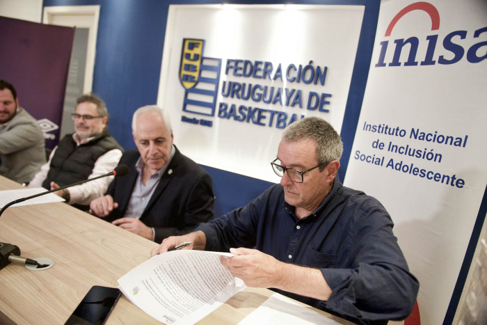 Presidente del Inisa, sentado, firma un documento.