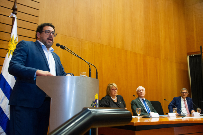 Secretario de Presidencia en un podio diserta frente a dos micrófonos