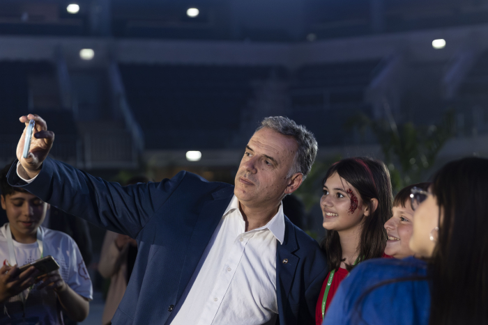 Orsi se toma una fotografía con celular junto a estudiantes en la Olimpíada de Robótica de Ceibal.