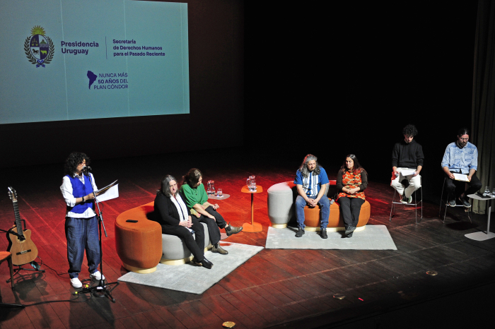 Directora de la Secretaría de Derechos Humanos junto a varias personas en el escenario.