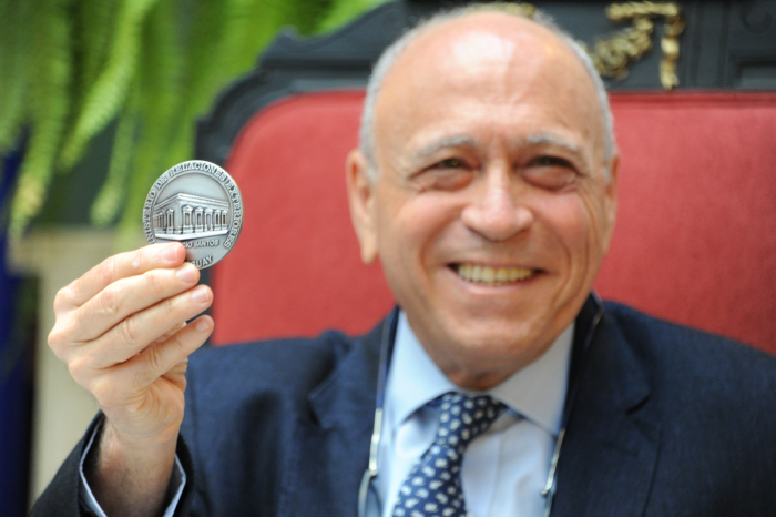 Primer plano del médico Henry Cohen sonriendo con una medalla en su mano.