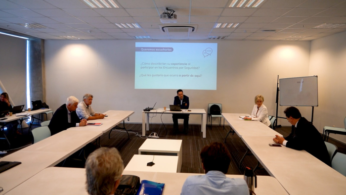 Plano general de la sala de reuniones con los participantes y autoridades sentados en mesa.