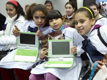 Escolares mostrando su computadora, entregada por el Plan Ceibal