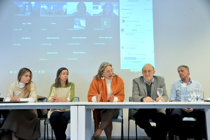 Secretaria de Derechos Humanos de Presidencia diserta sentada en mesa junto a cuatro participantes del encuentro.