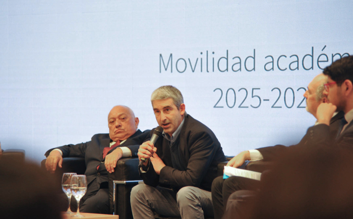 Caggiani sentado en un sillón hablando con micrófono junto a otras autoridades 