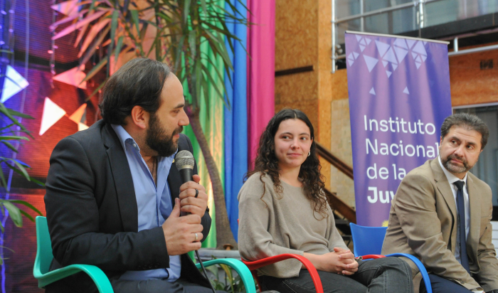 Ministro de Desarrollo Social, Gonzalo Civila, sentado con un micrófono en la mano, acompañado de la directora del INJU, Eugenia Godoy.