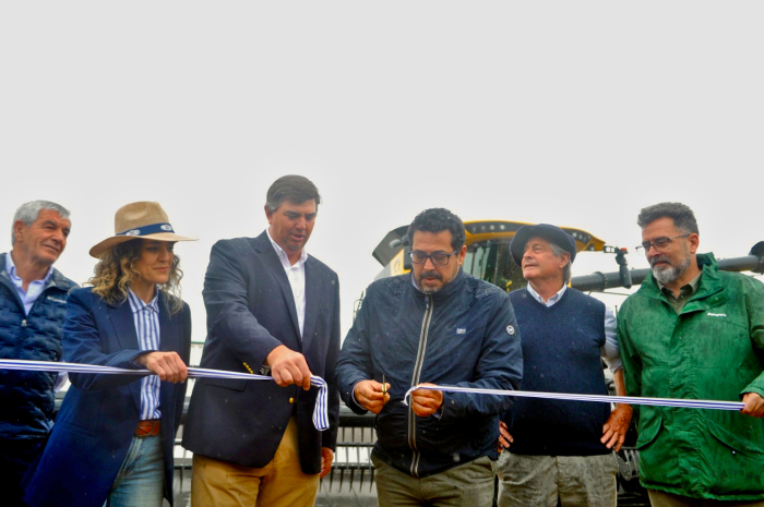 Secretario de la Presidencia, Alejandro Sánchez, corta una cinta inaugurando la cosecha de trigo. A su lado, un directivo de la Asociación Agro-Pecuaria de Dolores sostiene la cinta.