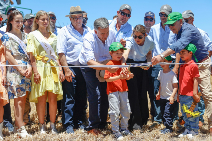 Presidente Yamandú Orsi sostiene una cinta de inauguración, que es cortada por un niño con una tijera, rodeado de personas