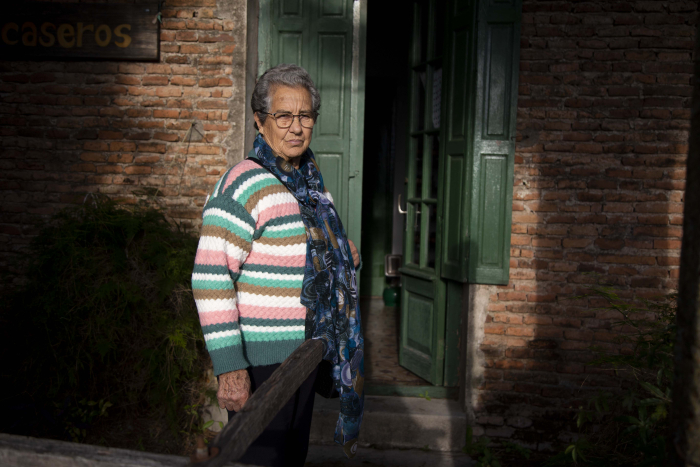 Señora de unos 80 años frente a la puerta de su casa