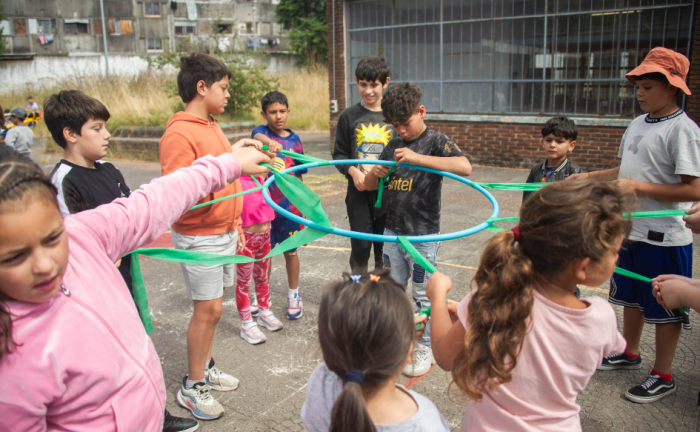 Niños juegan con un aro de plástico en el patio de la escuela pública n°317